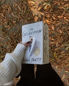 a person holding up a book in front of their face with the title, the goldfinch