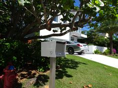 a mailbox in the grass near a fire hydrant and house with cars parked nearby