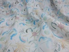 a close up view of a white fabric with blue and green designs