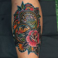 a colorful tattoo on the leg of a person with flowers and an oval frame around it