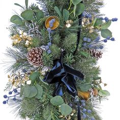 a christmas wreath with pine cones and blue berries