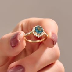 a woman's hand holding an engagement ring with blue and white diamonds on it