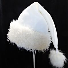 "Novelty Santa hat is made up in a creamy and cozy winter white or ivory tone poly fleece fabric. Hat is styled in the classic Santa slouch cone and is accented with a soft matching faux fur fabric turn up brim with a faux fur pompom on the top. Proportions of the hat are generous and will fit most head sizes, ladies or gents.  Measurement for opening for your head is 24-25\" circumference and the length is 20\". Check measurements to make sure this size will work for you.   Custom orders for si White Christmas Hat, White Short Brim Felt Hat For Winter, White Brimmed Felt Hat For Party, White Mini Hats For Winter Party, Adjustable White Felt Hat For Winter, Adjustable Cream Winter Felt Hat, White Beanie Costume Hat For Winter, White Winter Hat, One Size Fits Most, White Brimmed Felt Hat For Winter