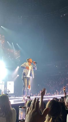 a man standing on top of a stage with his hands up in front of him