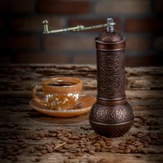 a coffee grinder sitting on top of a wooden table next to a cup of coffee