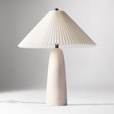 a white table lamp sitting on top of a white floor next to a light bulb