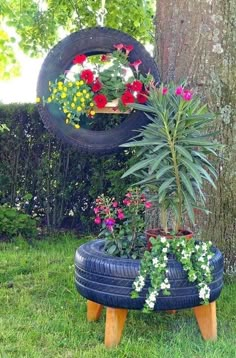 a tire planter with flowers in it sitting next to a tree