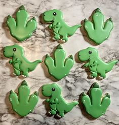 green dinosaur cookies sitting on top of a marble counter