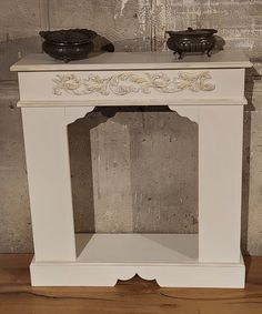 a white table with two black bowls on top of it and a wall behind it