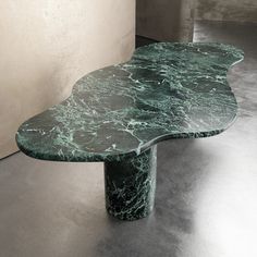 a green marbled table sitting on top of a floor next to a white wall