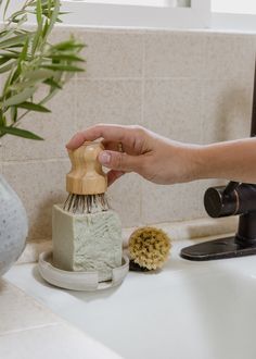 a person cleaning a sink with a brush and soap dispenser on it