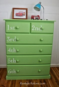 a green dresser with numbers painted on it and a lamp next to the drawers in front