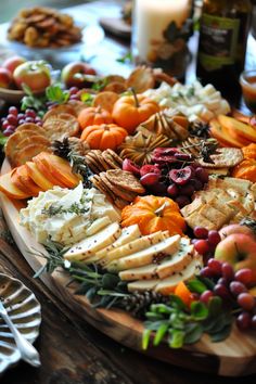 an assortment of cheeses and fruits on a wooden platter with candles in the background