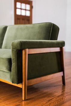 a green couch sitting on top of a hard wood floor