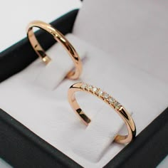 two gold rings sitting in a box on top of a table