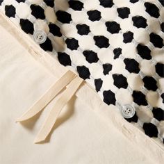 a black and white cow print blanket with buttons on the side, next to a pair of scissors