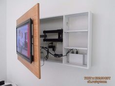 a tv mounted to the side of a white wall next to a wooden framed object