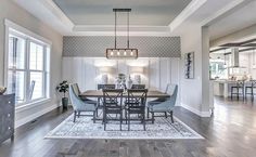 a dining room table with chairs and a rug on the floor in front of it