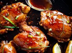 chicken wings with sauce and lemon wedges in a skillet, ready to be eaten