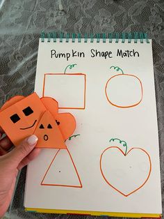 a hand holding two pieces of paper with pumpkin shape match on it next to a sheet of paper that says pumpkin shape match