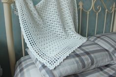 a white crocheted blanket sitting on top of a bed next to a pillow