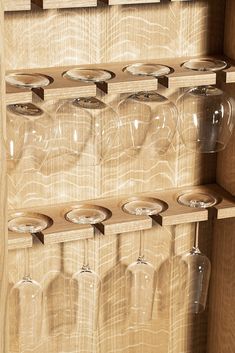 wine glasses are lined up on wooden shelves