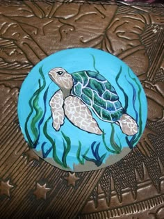 a blue plate with a turtle painted on it's side and seaweed in the background