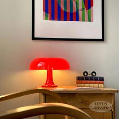 a red lamp sitting on top of a table next to a wooden dresser and chair