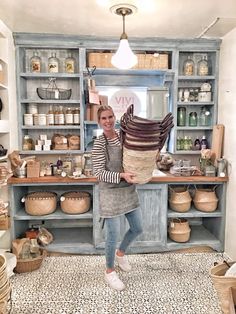 a woman standing in front of a kitchen counter filled with lots of boxes and baskets