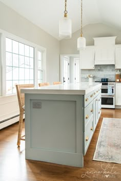 a large kitchen with white cabinets and wood flooring, along with an island in the middle