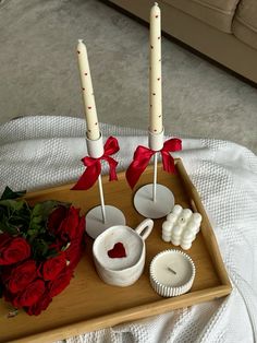 two candles are sitting on a tray with roses and cupcakes