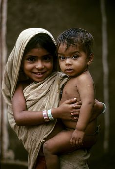 two young children standing next to each other with one holding the other in his arms