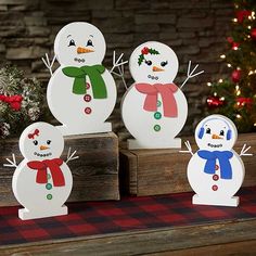 four snowmen are standing in front of a christmas tree