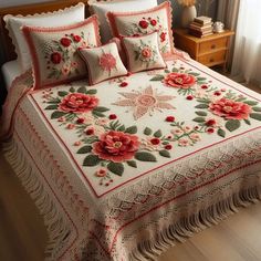 a large bed with red flowers on it and fringes around the edges is shown