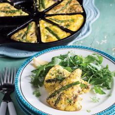 an omelet with asparagus and spinach on a plate next to a fork