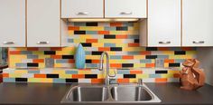 a kitchen with white cabinets and colorful tiles on the backsplash, along with a stainless steel sink