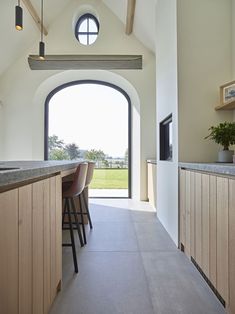 a kitchen with an arched window and bar stools next to the counter top area