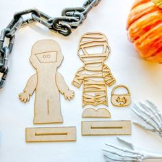 some cut outs are laying out on a white surface next to pumpkins and chains