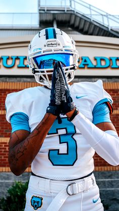 a football player is holding his helmet in front of the stadium sign that reads, university of north carolina