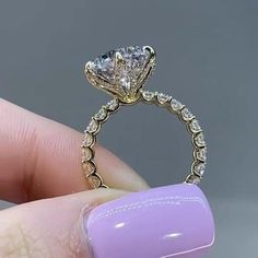 someone is holding their engagement ring with the diamond in it's center and on her finger