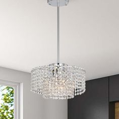 a chandelier hanging from the ceiling in a room with grey walls and windows