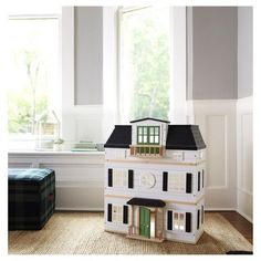 a white doll house sitting on top of a wooden floor in front of a window