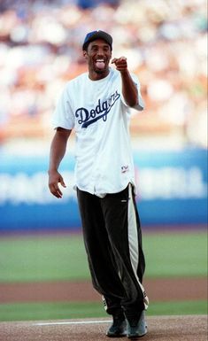 a man standing on top of a baseball field wearing a white shirt and black pants