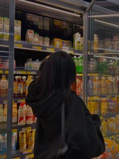 a woman is standing in front of a display case with drinks and condiments