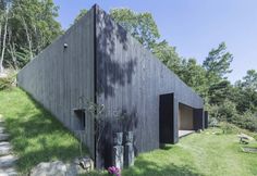 the house is made out of black wood and has an open door on one side