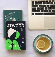 there is a cup of tea next to a book and a laptop on the table