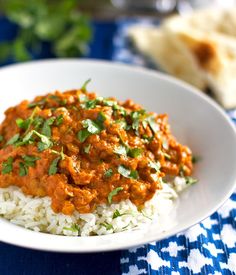 a white bowl filled with rice covered in sauce and garnished with cilantro