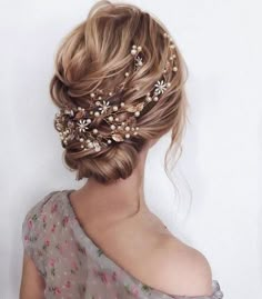 a woman wearing a hair comb with flowers and pearls on it's head, in front of a white wall