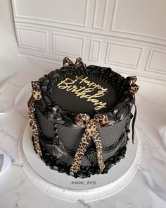 a black and leopard print birthday cake on a table