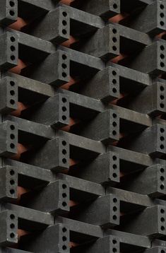 a close up view of concrete blocks with holes in the middle and red bricks behind them